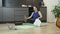 Woman sitting in lotus pose is drinking water and wiping her face with towel after online fitness training at home. Online aerobic