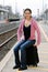 Woman sitting on luggage waiting for train