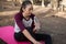 Woman sitting on mat drinking water after exercising