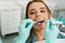 Woman sitting in medical chair while dentist fixing her teeth