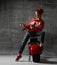 Woman sitting on motorcycle bicycle scooter retro pinup style point hands at the corner in red blouse and jeans