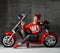 Woman sitting on motorcycle bicycle scooter retro pinup style pointing finger at the corner in red blouse and jeans