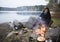 Woman Sitting Near Bonfire On Lakeshore During Camping