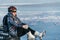 Woman sitting near her bike on ice. The girl cyclist stopped to rest. She sits on the wheel and enjoys the beautiful