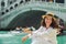 woman sitting near rialto bridge in venice italy looking at grand canal with gondolas