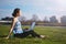 Woman sitting in park on the green grass with laptop. Computer screen mockup. Student studying outdoors. Copy space for text. Beau