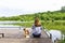 Woman sitting on the pier with her puppy and admiring the landscape