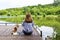 Woman sitting on the pier with her puppy and admiring the landscape