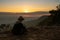 Woman sitting reading and writing looking out at natural view