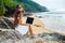 Woman sitting on the rock with laptop