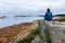 Woman sitting on a rock and looking away at the rough but beautiful coast of Brittany