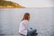 Woman sitting on rocks along lakefront at sunset