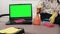 Woman sitting on sofa with cleaning agents near laptop with green screen