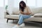 Woman sitting on sofa at home back and stomach pain during menstruation, women& x27;s day, women& x27;s health problems