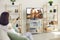 Woman sitting on sofa at home and watching movie or TV show on big television set