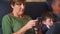 Woman sitting on the sofa takes a look at her cell phone while the rest of the family watches television