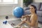 Woman sitting on sports mat and smiling at camera while enjoying healthy meal after workout