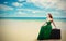 Woman sitting on suitcase enjoying ocean view