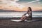 Woman sitting on surfboard on sand on beach