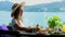 Woman sitting at table in cafe with sea view drinking orange juice