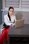 woman sitting by the table on couch in grey room - office and use laptop. big boss. important, confident women