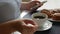 Woman sitting at the table, drinking coffee with cinnamon buns, stiring coffee and looking at smartphone