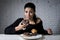 Woman sitting at table feeling guilty forgetting diet eating dish full of junk sugary unhealthy food