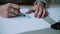 Woman sitting at table, holding pencil and coloring sketch of shoes on paper. Slider right, camera goes by circle. 4K