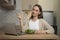 A woman is sitting at a table in the kitchen and enjoying a nutritious salad for lunch and using a laptop