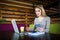 Woman sitting at table with laptop, cup and notebook look at mobile phone