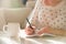 Woman sitting at the table, writing in the notebook and drinking coffee in nice light home interior. Working at home. Freelancer.