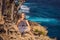 Woman sitting on a tree against the background of the sea Angel`s Billabong in Nusa Penida, Bali, Indonesia. Bali Travel