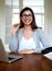 Woman sitting upright smiling at home office desk.