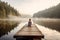 Woman sitting on a wooden pier on a lake in the misty morning. Generative AI