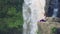 Woman sitting in yoga lotus pose on the edge next to Tegenungan Waterfall