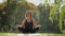 Woman sitting on yoga mat and practicing yoga exercise outdoors in sunny day. Wide shot
