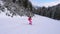 Woman Skier Go Down On Ski Route Down Against Mountain Slopes Among Pine Forest