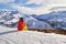 Woman skier looking at the mountain peaks in the French Alps, on Les Sybelles ski domain, above Saint-Jean-d`Arves village, France