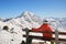 Woman skier relaxes on a bench and looks at Parpaner Rothorn peak and snowy mountain ridge. Vacation, tourism in Arosa Lenzerheide