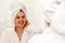 Woman of Slavic appearance in dressing gown smiles in mirror