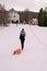 Woman with a sled on a rope walks along the top of a hill. Back view