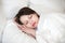 Woman sleeping in bed on orthopedic pillow covering with duvet