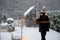 Woman in sleepwear and hat goes out on her snowy backyard