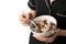 Woman in sleepwear holding bowl with whole wheat flakes, blueberry and coconut