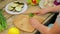 Woman slices green long chili pepper with a knife on a wooden board. time laps