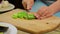 Woman slices green long chili pepper with a knife on a wooden board. time laps