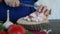 Woman slices pork fat with meat layers and puts it on a wooden surface, close-up. Slicing streaky pork on wooden board