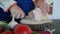 Woman slices pork fat with meat layers and puts it on a wooden surface, close-up. Slicing streaky pork on wooden board