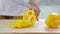 Woman is slicing bell pepper or sweet pepper on wooden cutting board