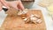 Woman slicing crimini mushrooms on wooden cutting board. Step by step mushroom pizza recipe